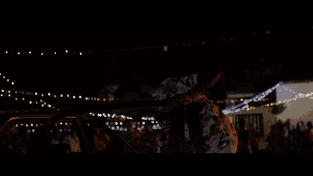 a group of people are dancing under a string of lights .
