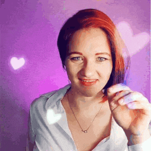 a woman with red hair is holding a purple object in her hand in front of a purple background .