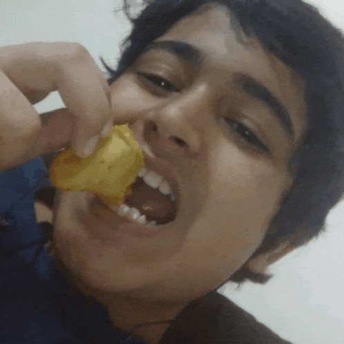 a young man is eating a piece of food with his mouth wide open