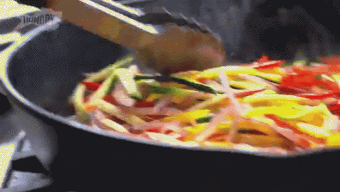 a pan of vegetables is being stirred with a wooden spoon ..