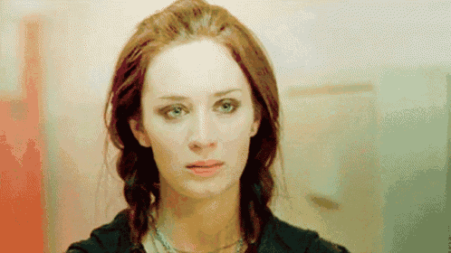 a woman with red hair and blue eyes is looking at the camera with a sad look on her face .