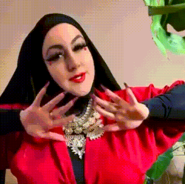 a woman wearing a black hijab and a red jacket is making a face .