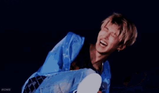a man in a blue jacket is laying on the ground laughing