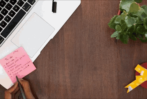 a person writes on a pink sticky note that says to do list