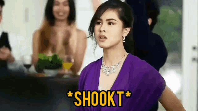 a woman in a purple dress says shookt in front of a group of people