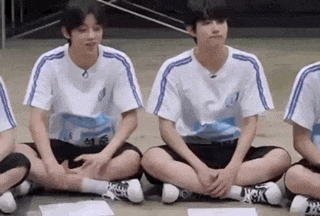 a group of young men are sitting on the floor with their feet crossed .