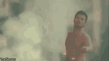 a shirtless man is standing in front of a fire in a field .
