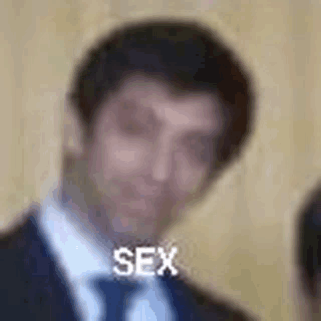 a blurry picture of a man in a suit and tie with the word sex on his face .