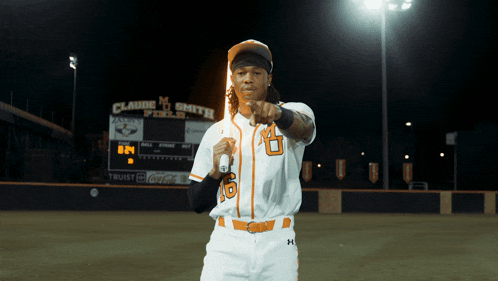 a baseball player in front of a scoreboard that says claude m smith field