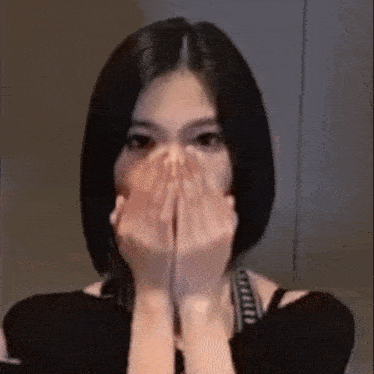 a woman with short hair is covering her face with her hands
