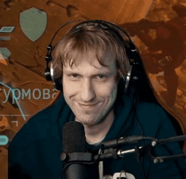 a man wearing headphones and a hoodie is sitting in front of a microphone .