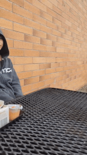 a person wearing a hoodie that says nc sits at a table