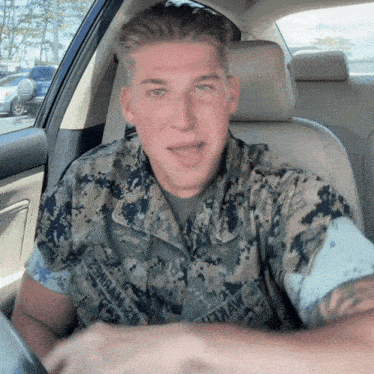 a man in a military uniform is sitting in the driver 's seat of a vehicle