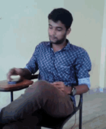 a man in a plaid shirt sits in a chair with his legs crossed