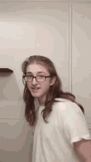 a young man with long hair and glasses is smiling for the camera
