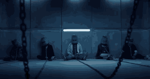 a group of people are chained to a wall and wearing masks