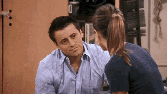 a man and a woman are looking at each other and the man is wearing a striped shirt