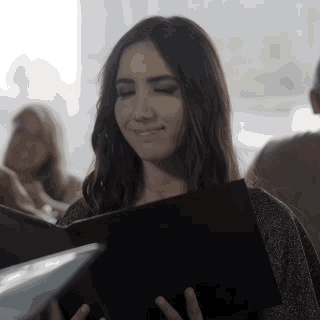 a woman is smiling while holding a book that says ' i love you ' on it