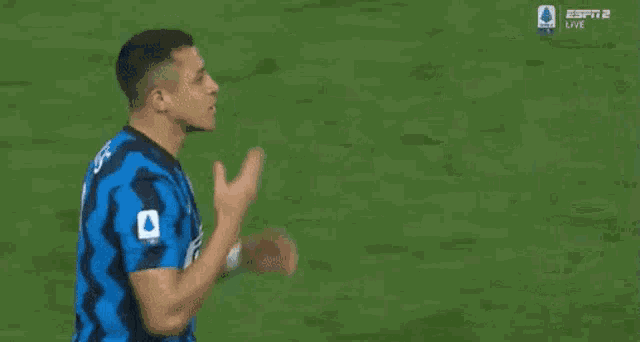 a soccer player is pointing at another player on the field while another player looks on .