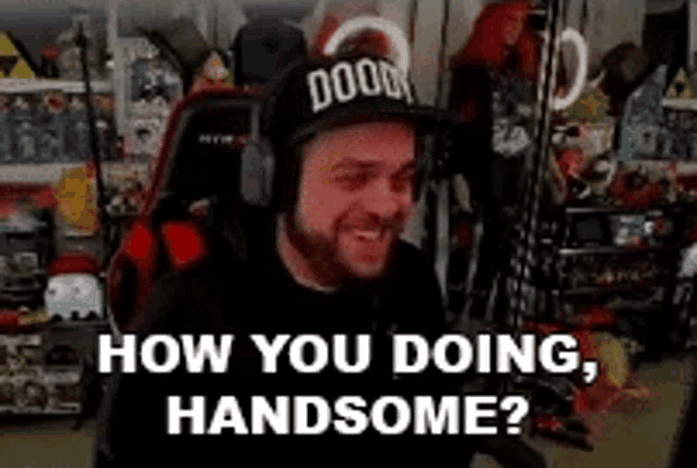 a man wearing headphones and a hat is sitting in a chair in a video game room .
