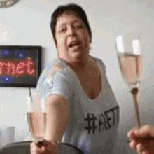 a woman in a blue shirt is holding a glass of wine .