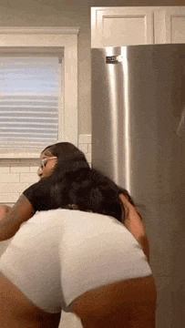 a woman in white shorts is dancing in a kitchen .