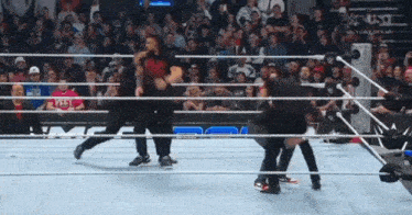 a group of wrestlers are fighting in a wrestling ring with a crowd watching .