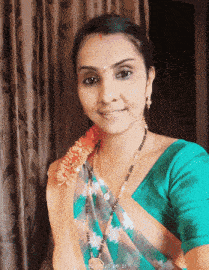 a woman wearing a green top and a necklace with the date 27 09 31 on it