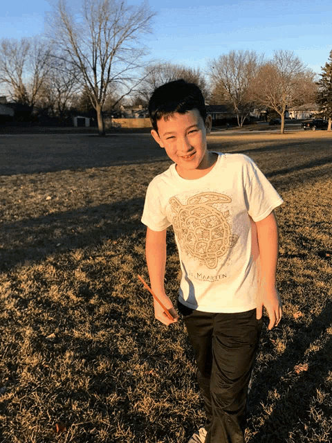 a young boy wearing a white shirt with a turtle design on it