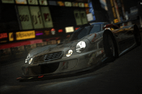 a silver sports car is driving down a city street at night