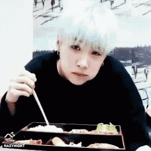 a boy with green hair is eating a meal with chopsticks
