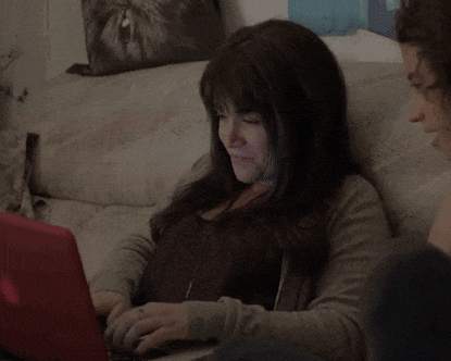 a woman is sitting on a couch using a laptop