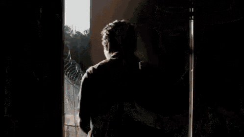 a man is standing in a doorway looking out a window .