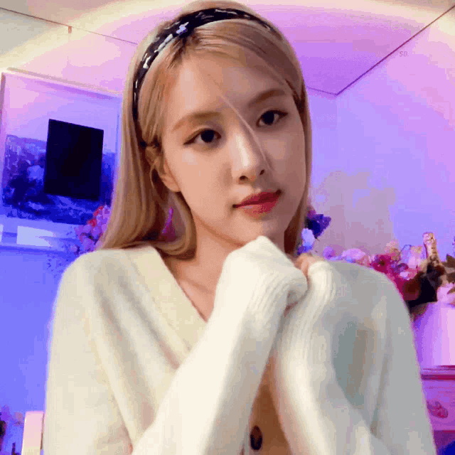 a blonde woman wearing a headband and a white sweater