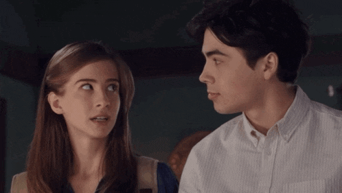 a man and a woman are looking at each other in a room