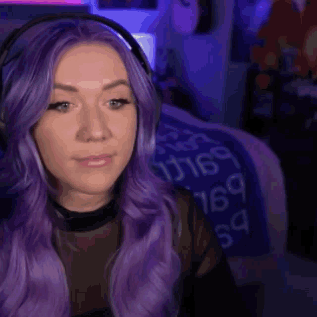 a woman with purple hair is wearing headphones and says hi !
