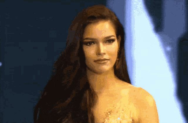 a woman with long hair is wearing earrings and a gold dress