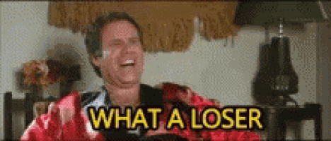a man is laughing and saying `` what a loser '' while sitting on a couch .