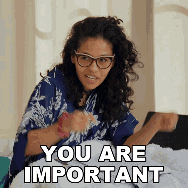 a woman wearing glasses is sitting on a bed and says you are important