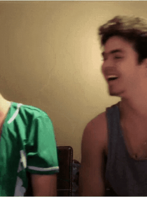 a man in a green shirt is laughing next to another man
