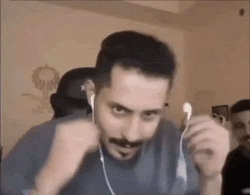 a man with a mustache is wearing headphones and making a face .