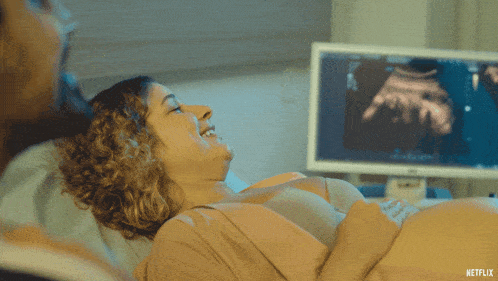 a pregnant woman is smiling while laying in a hospital bed