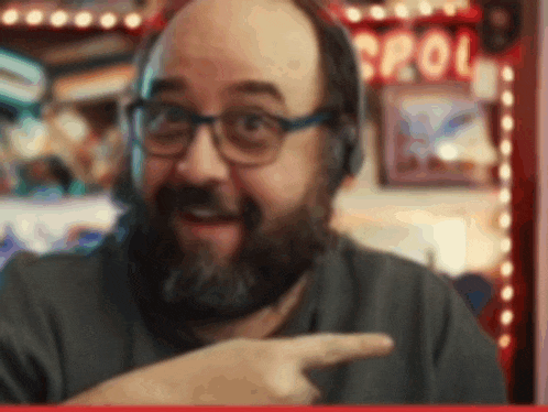 a man with glasses and a beard is pointing to something