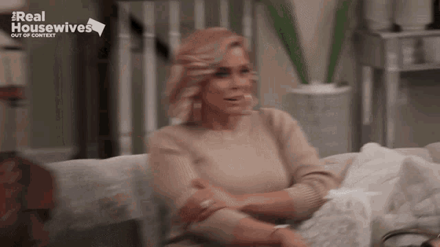a woman is sitting on a couch with a real housewives logo in the background