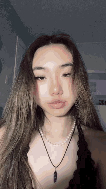 a woman with long hair wearing a black top and a necklace