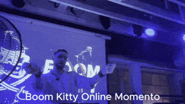 a man stands in front of a screen that says boom kitty on it