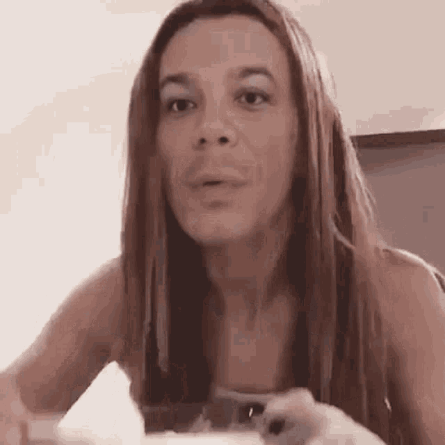 a woman with long hair is sitting at a table with a spoon in her hand .