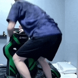 a man in a blue shirt is squatting down on a green chair .