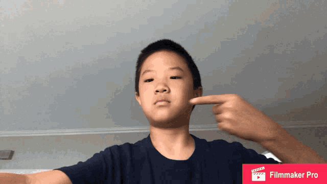 a young boy is pointing at his face with a filmmaker pro logo in the corner
