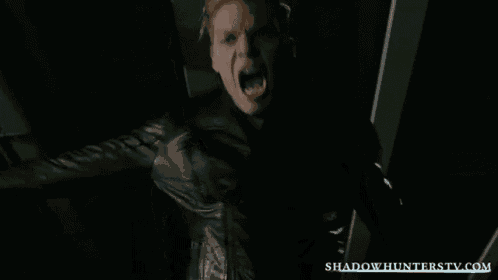 a man in a black jacket is screaming in the dark .